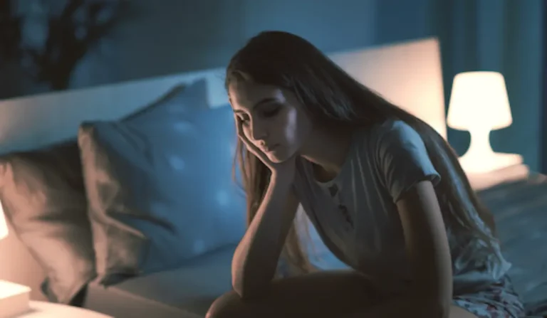 Femme somnolant sur le bord de son lit la nuit.